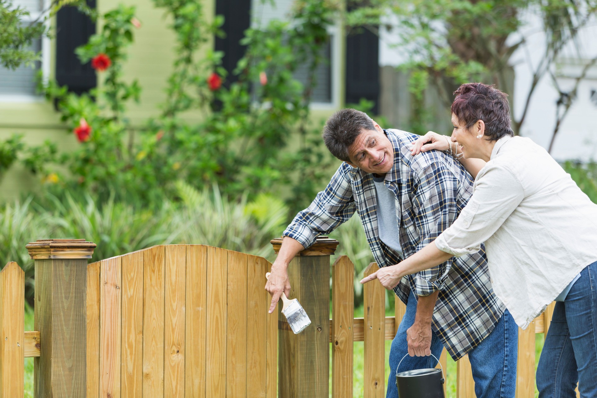 Mature couple painting fence