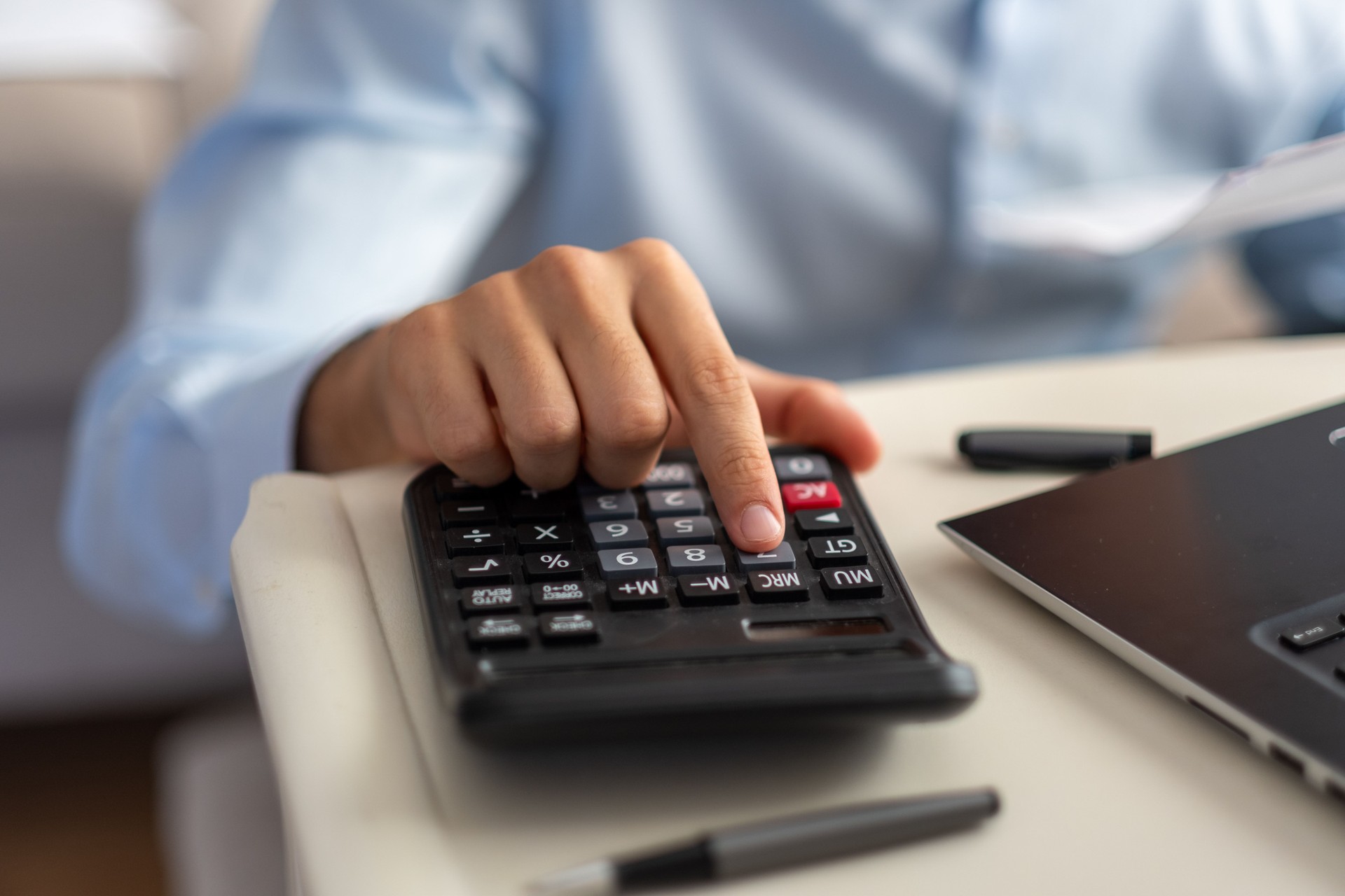 Businessman calculating tax using calculator and laptop at home office